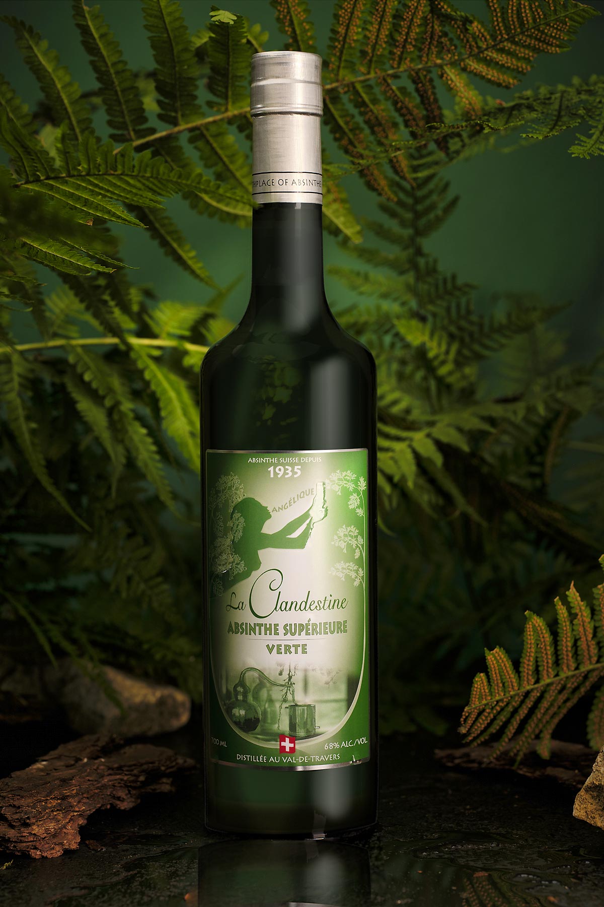 Bouteille d’absinthe verte “La Candestine” posée sur fond végétal, logo argenté et étiquette verte antique.