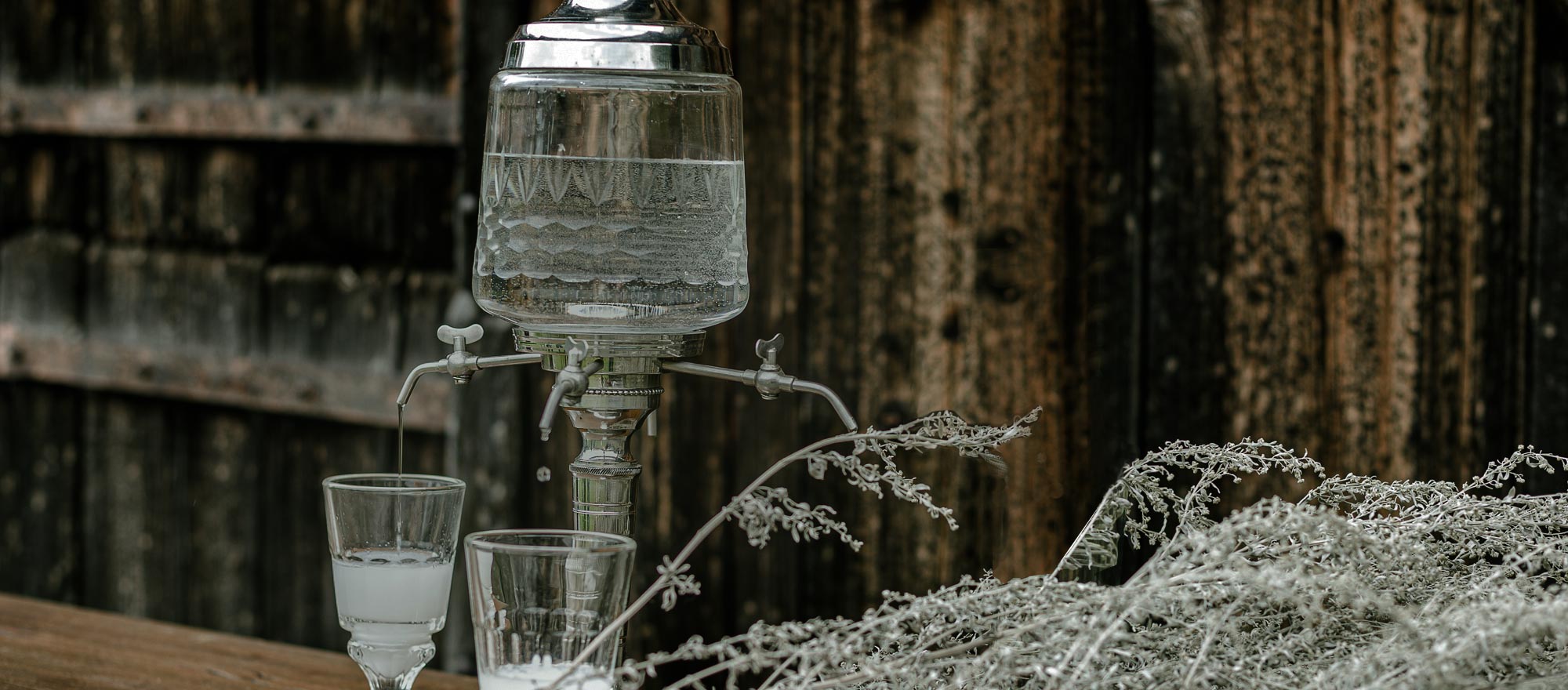 Verseur d’absinthe et verres sur table, avec eau glacée fendant une boule de sucre sur la cuillère, prêt pour le rituel traditionnel.