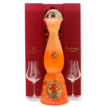 Tequila Clase Azul Día de Muertos Aromas 2023: bouteille orange festive en forme sculpturale avec capuchon doré, accompagnée de deux verres et coffret rouge.