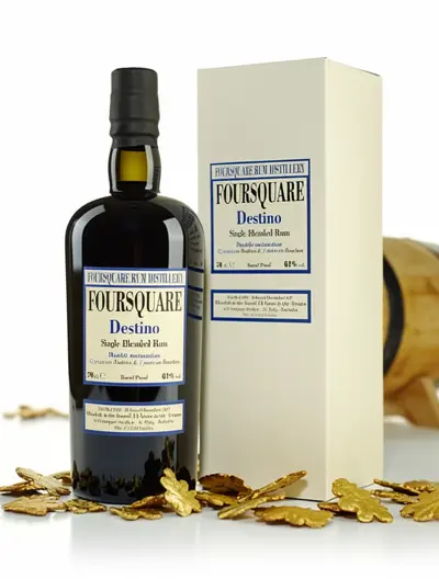 Bouteille de rhum arrangé Foursquare Destiny avec boîte, entourée de copeaux dorés, prêt à la dégustation. conservation rhum arrangé ouvert.